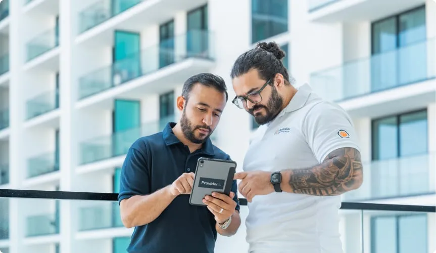 Two Precision Inspection engineers reviewing a booking on a tablet outside a residential building